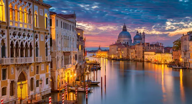 View of Venice at sunset, showing the Salute Church and a canal leading out to sea