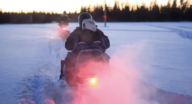 Image of a person riding a snowmobile from behind 